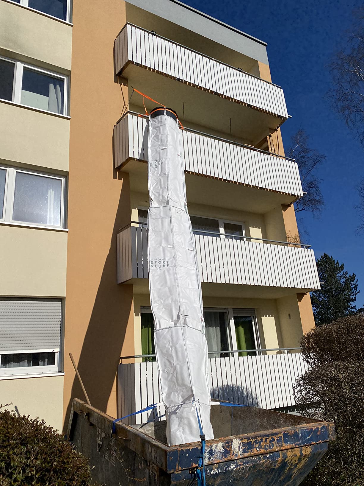 Goulotte à gravats flexible Stortslurf® installée depuis un balcon
