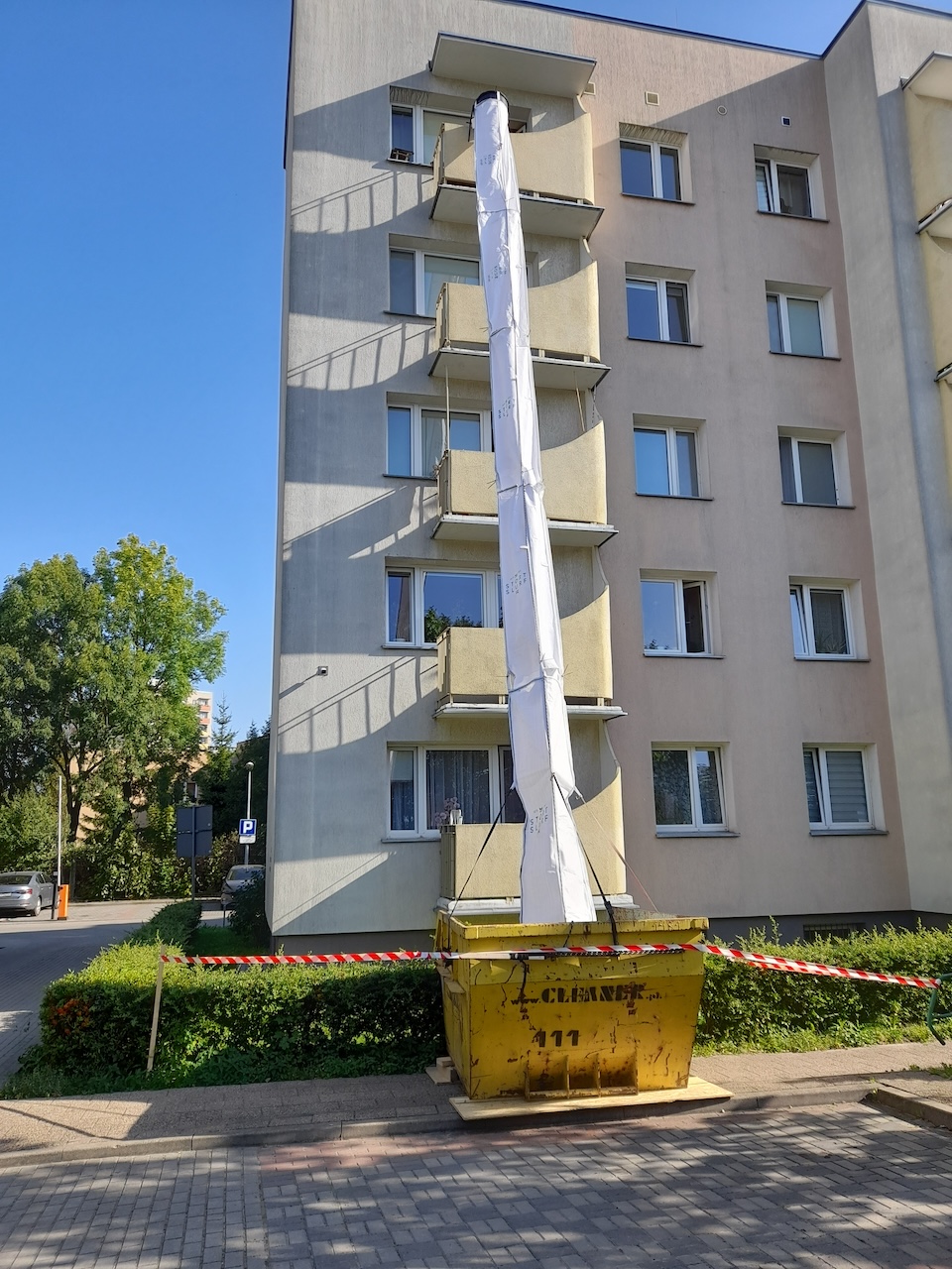 Goulotte à gravats flexible installée sur la façade d’un immeuble vers une benne de chantier